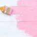 Close up paintbrush painting pink color on a white wooden table