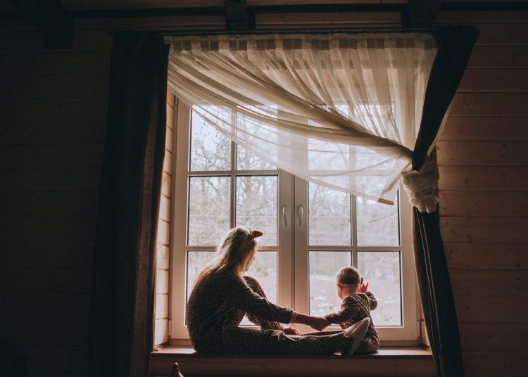 Mother with baby sitting at the window and play