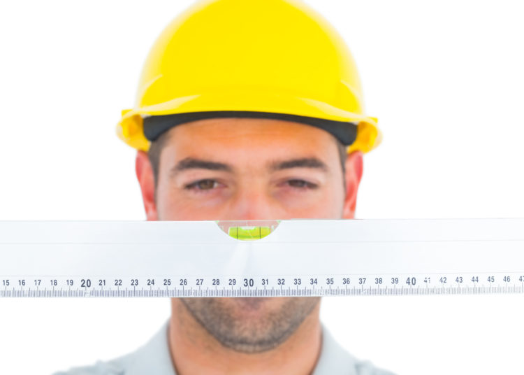 Handyman looking at spirit level over white background