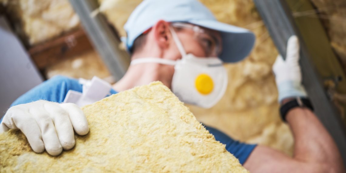Mineral Rock Wool Insulating Concept Photo. Worker with Piece of Insulating Wool in Hands.