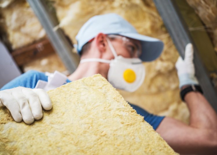 Mineral Rock Wool Insulating Concept Photo. Worker with Piece of Insulating Wool in Hands.