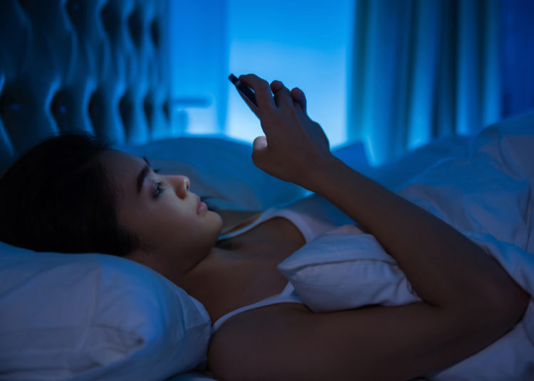 Asian women are using the smart phone on the bed before she sleeping at night.