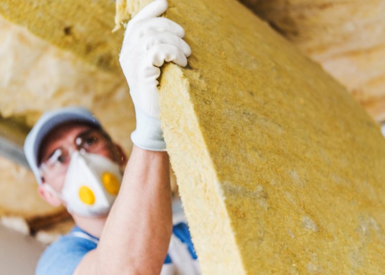 Caucasian Construction Worker with Piece of Insulating Material, Roof Insulating by Mineral Wool.