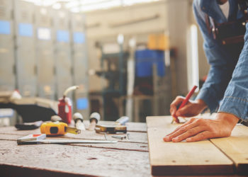 Carpenter working on woodworking machines in carpentry shop. woman works in a carpentry shop.