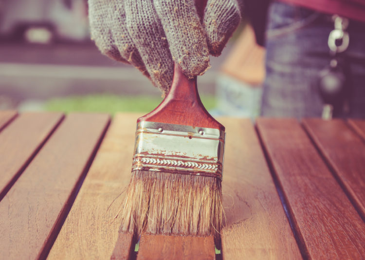 Close up paintbrush in hand and painting on the wooden table. Retro and vintage style