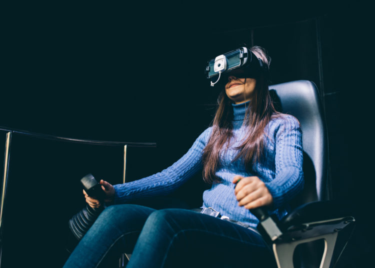 Young beautiful eastern woman sitting on a gaming chair testing augmented reality with 3D viewer - games, futuristic, augmented reality concept