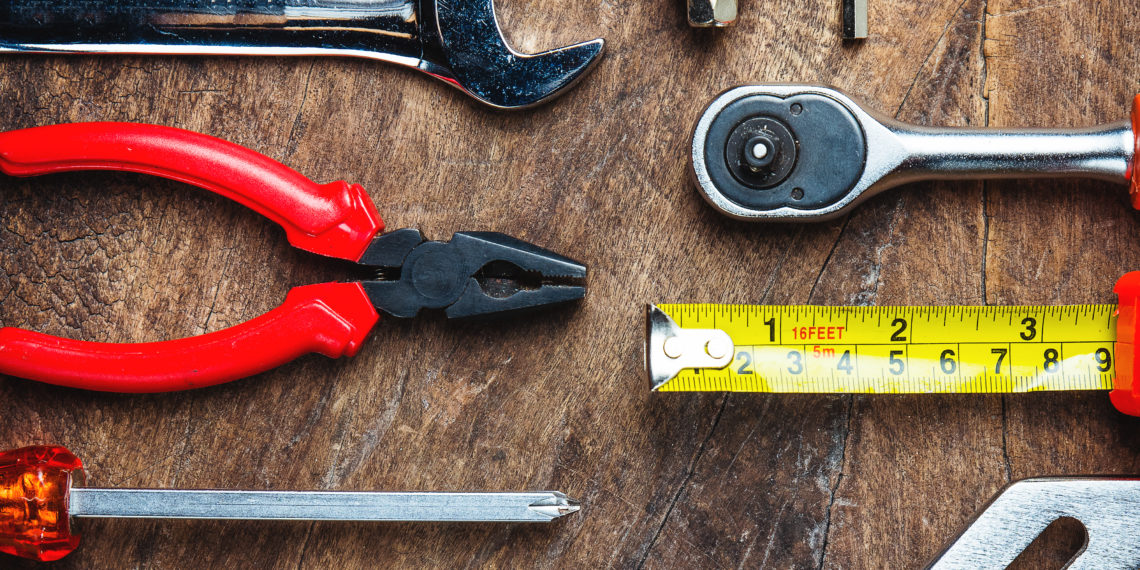 Set of construction tools on wooden board as wrench, hammer, pliers, socket wrench, spanner, tape measure, electric drill,safety glasses, screwdriver.