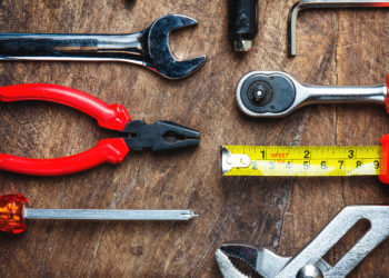 Set of construction tools on wooden board as wrench, hammer, pliers, socket wrench, spanner, tape measure, electric drill,safety glasses, screwdriver.