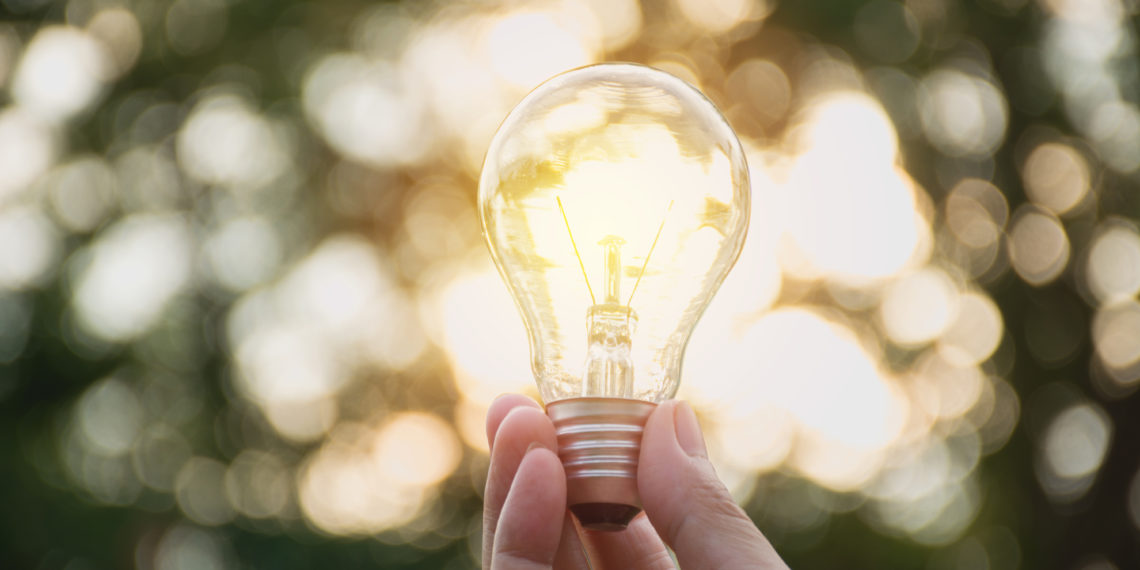 Hand of person holding light bulb for idea or success or solar energy concept.
