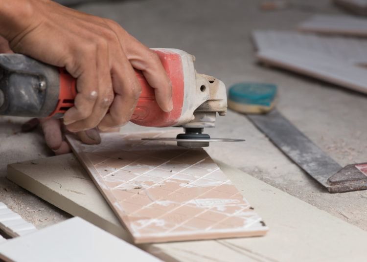 worker grinding a tile using an angle grinder at construction site