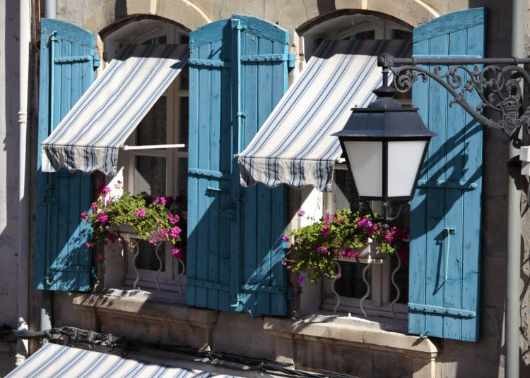 France provence style cottage windows, blue shutters and flower boxes.