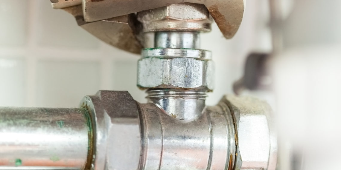 Close up of hand checking pipes with wrench