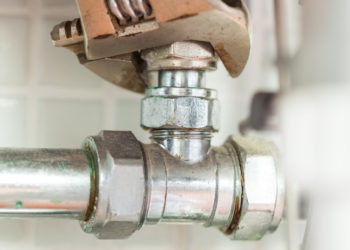 Close up of hand checking pipes with wrench