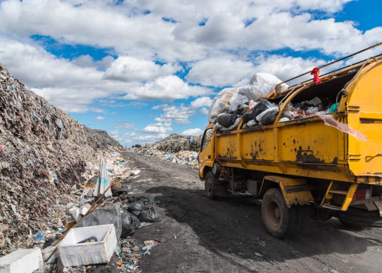 Dump trucks unloading garbage over vast landfill