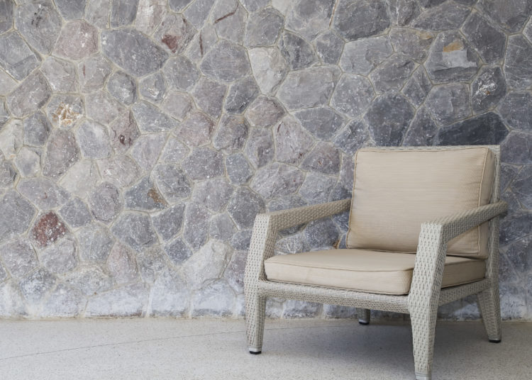 Outdoor furniture wicker chair with stone wall