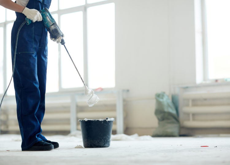 Painter in coveralls mixing whitewash in bucket