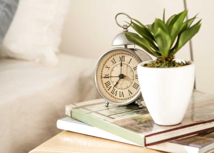 a vintage style alarm clock with roman number by the bed