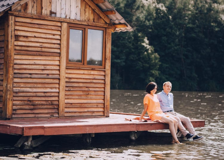 Young couple sitting next to wooden shed.