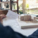 An architect working and looking at an architecture model with shop drawing paper on table