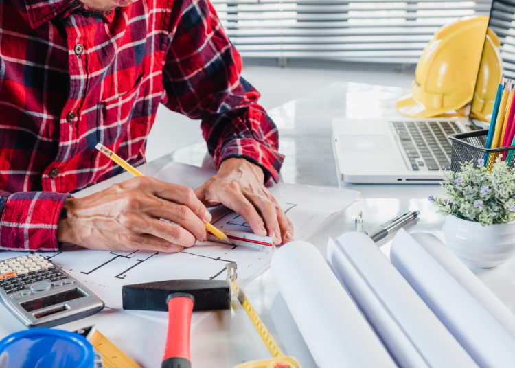 Business man interior designer working and drawing with blueprint and architectural project in construction office.