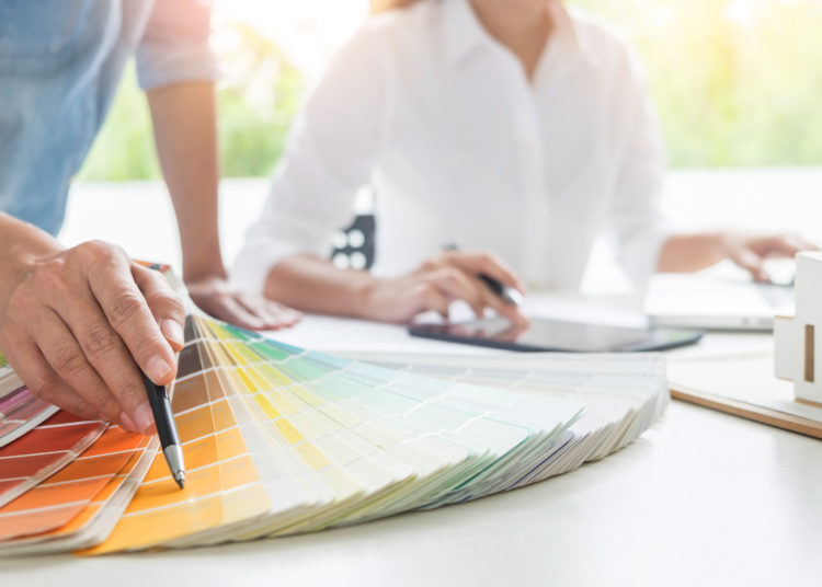 Creative or Interior designers teamwork with pantone swatch and building plans on office desk, architects choosing color samples for design project