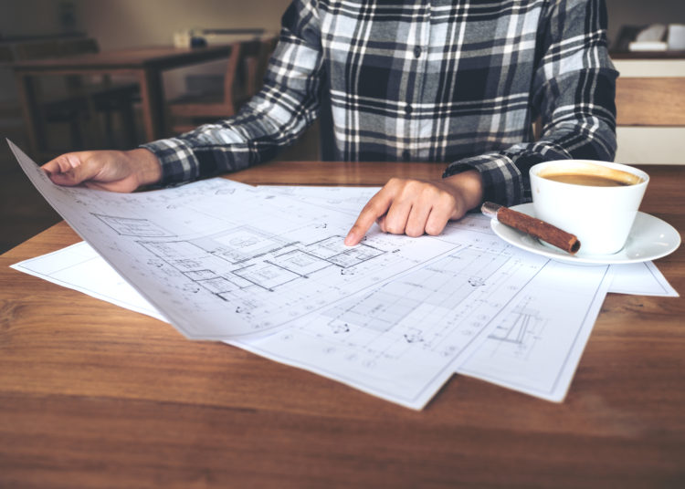 An architect working and pointing at shop drawing paper on table