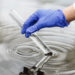 Researcher holds a test tube with water in a hand in blue glove