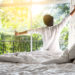man happy waking up in the bed rising hands to window in the morning with fresh feeling relax