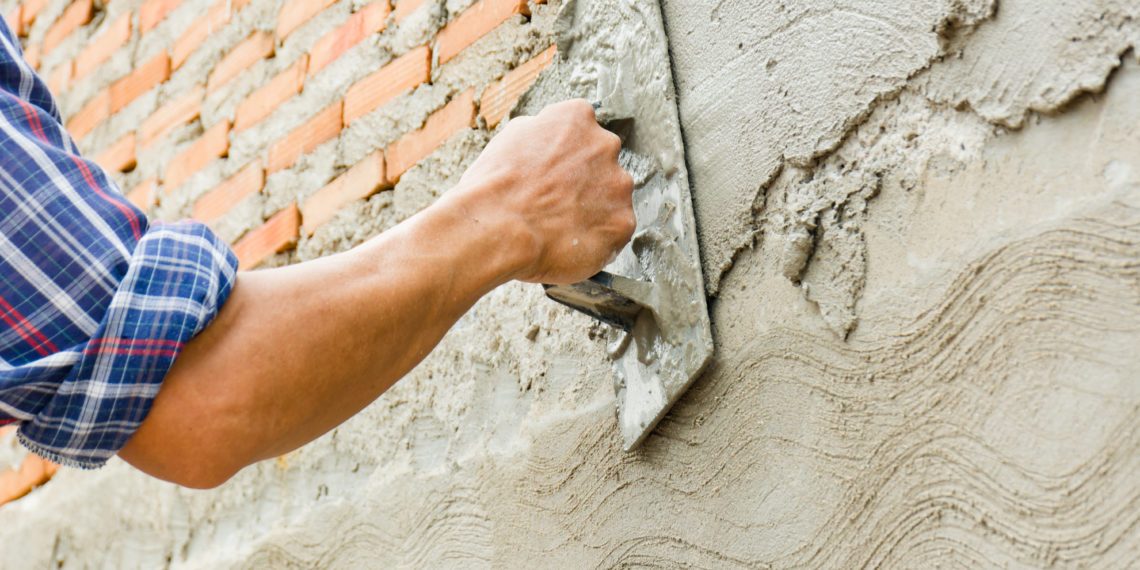 Builders are plastering the walls of the house with neatness. Have professional skills and high working experience. Concept of construction business.