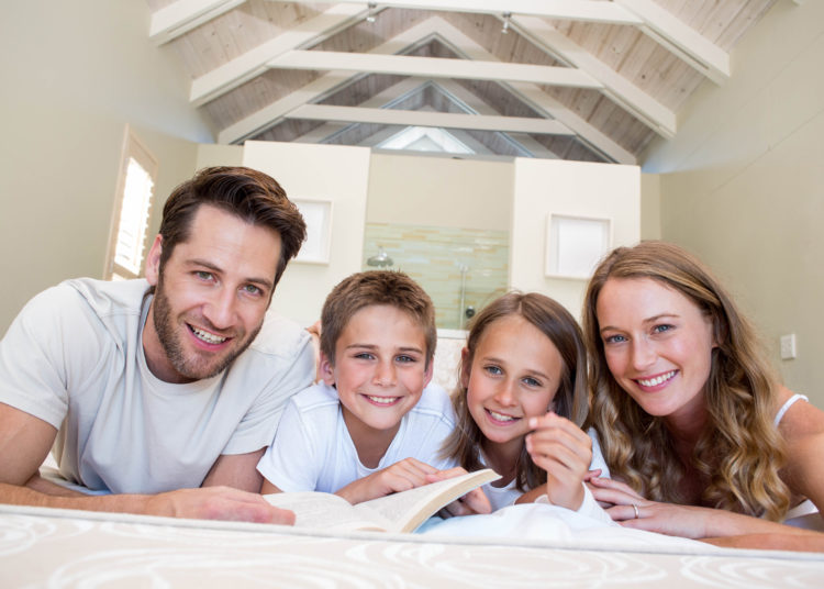 Happy family on the bed reading book at home in bedroom