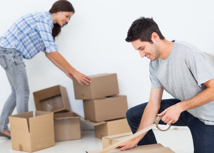 Woman and man wrapping boxes while they are moving home