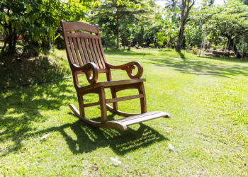 Empty rocking chair over grass at summer sunset