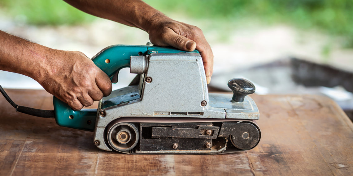 The carpenter uses power sander as a powerful tool in wood finis