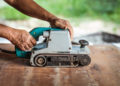The carpenter uses power sander as a powerful tool in wood finis