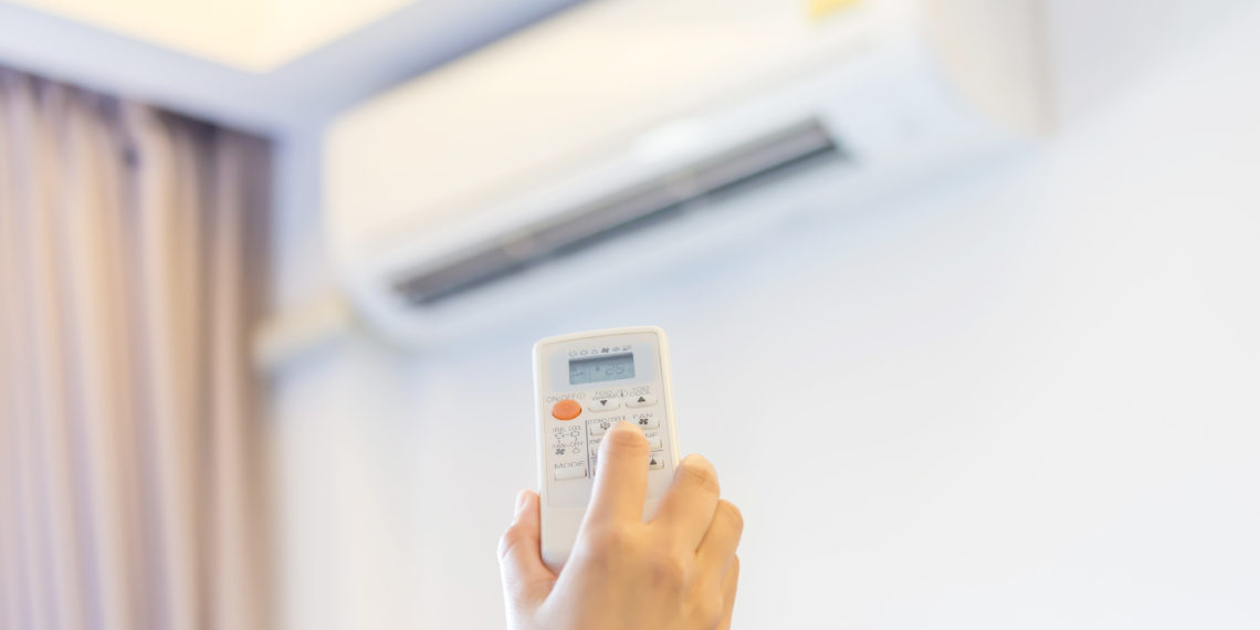 Hand hold remote control turn on air conditioner.