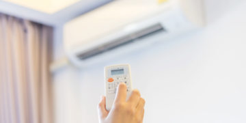 Hand hold remote control turn on air conditioner.