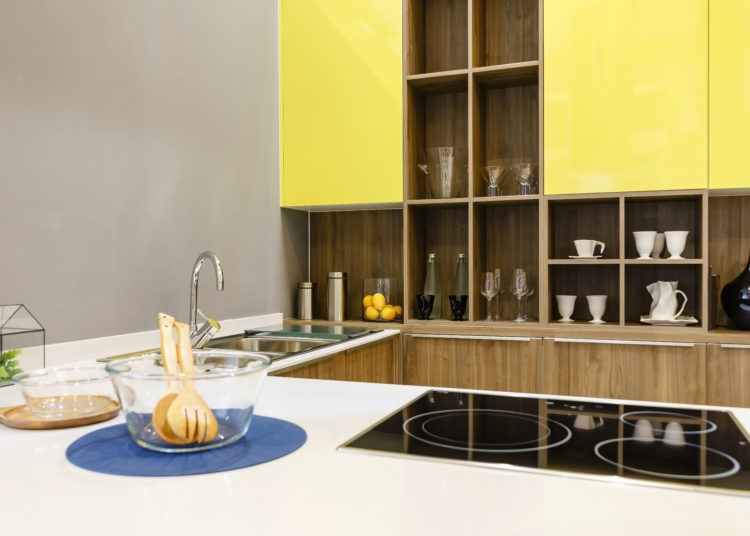 Modern kitchen furniture with contemporary kitchenware like hood, black induction stove and oven in house.