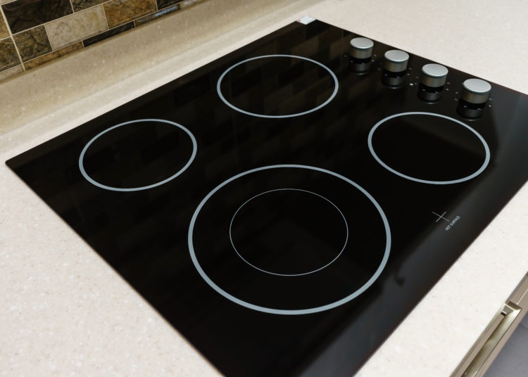 Modern black induction stove, cooker, hob or built in cooktop with ceramic top in white kitchen interior