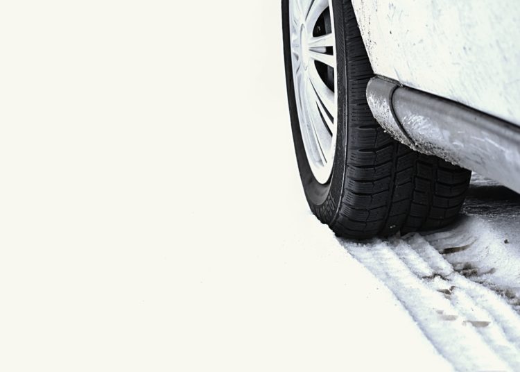 Car in winter. Tire on a snowy road in bad weather.