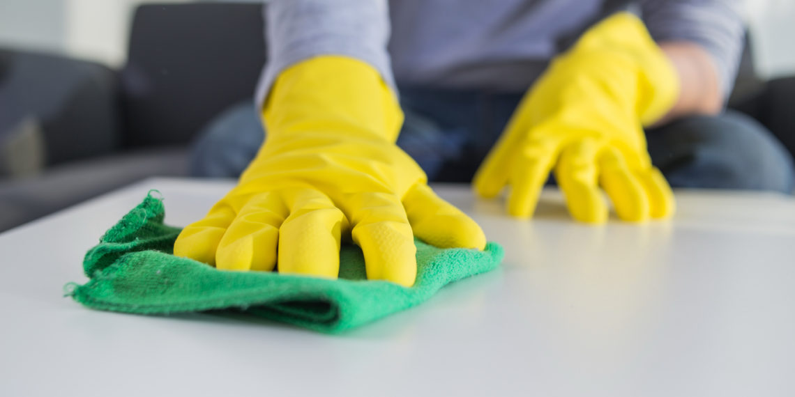 people, housework and housekeeping concept - close up of man hands cleaning table with cloth at home