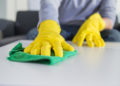 people, housework and housekeeping concept - close up of man hands cleaning table with cloth at home