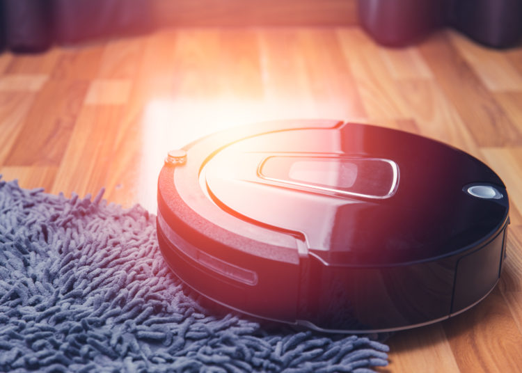 robot vacuum cleaner working on carpet at wooden floor room