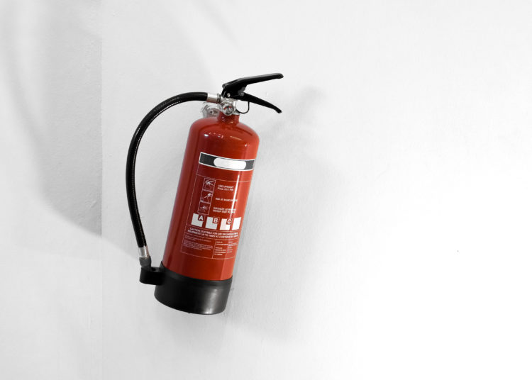 Red fire extinguisher on a white wall