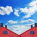 Red roof of new detached houses against blue sky.