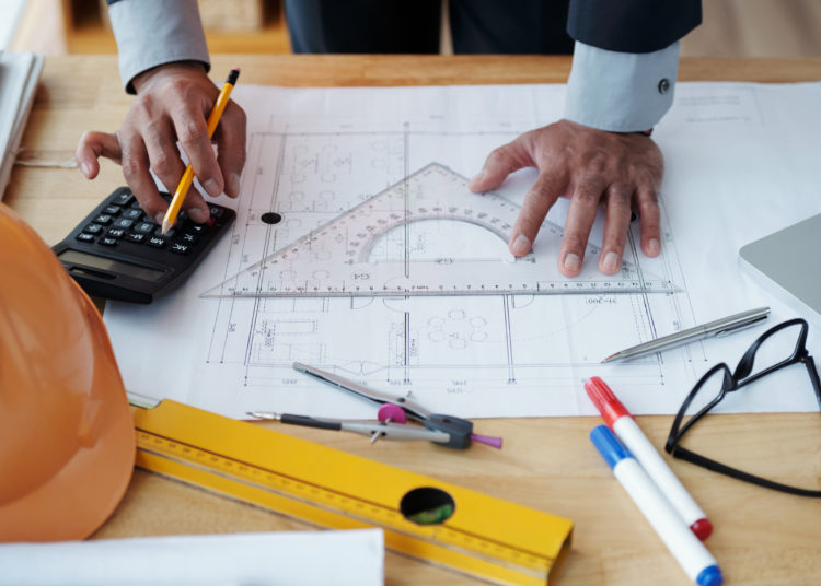 Hands of engineer checking construction plan on his table