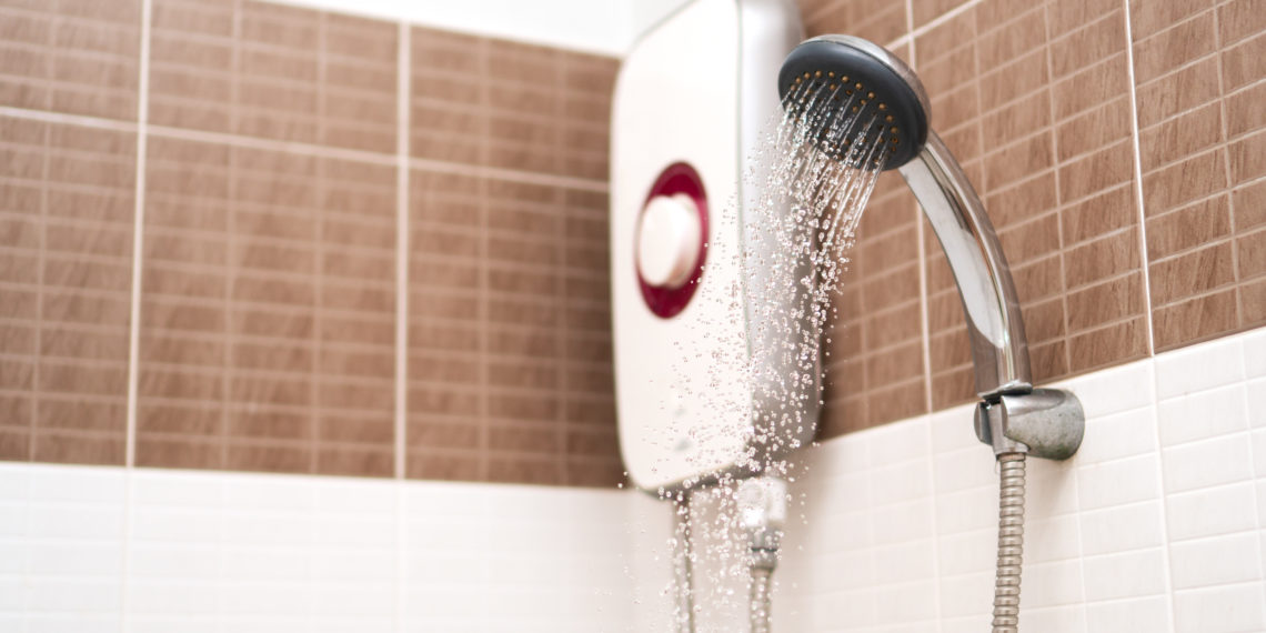 Shower cabin and water heater in a bathroom. Running water of shower faucet.