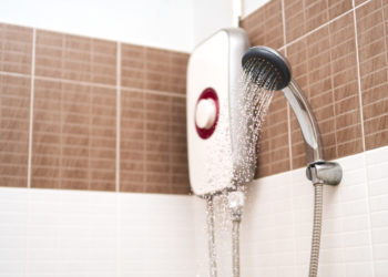 Shower cabin and water heater in a bathroom. Running water of shower faucet.