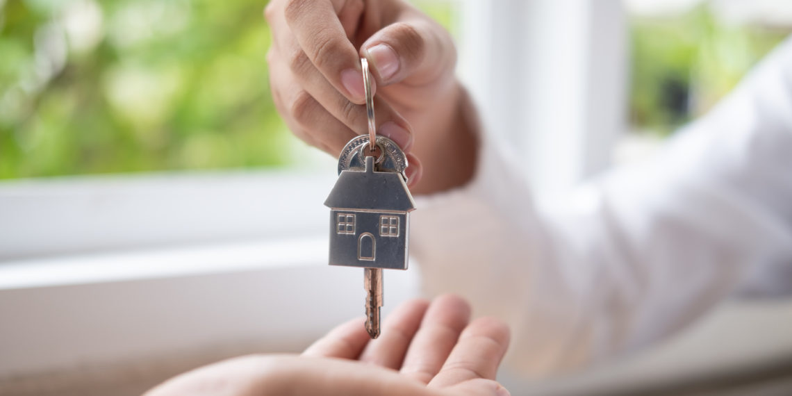Real estate agent hand giving a house keys to house buyer.