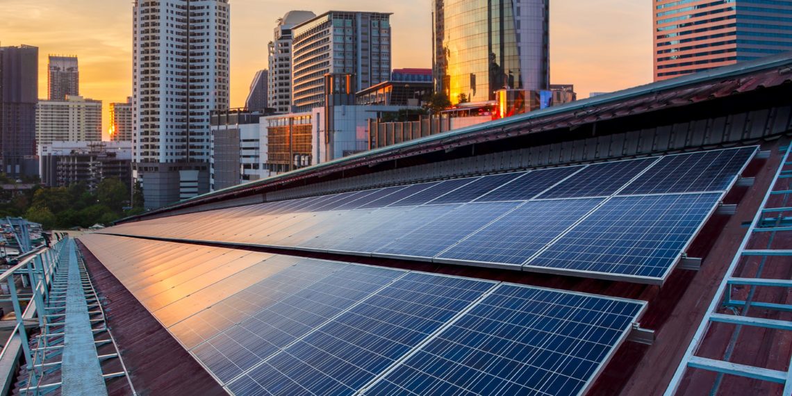 Solar Panel Photovoltaic installation on a Roof of factory, sunny blue sky background, alternative electricity source - Sustainable Resources Concept.
