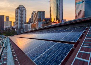 Solar Panel Photovoltaic installation on a Roof of factory, sunny blue sky background, alternative electricity source - Sustainable Resources Concept.